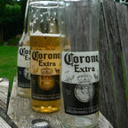 Two tall glasses one full sitting on the arm of a grey chair