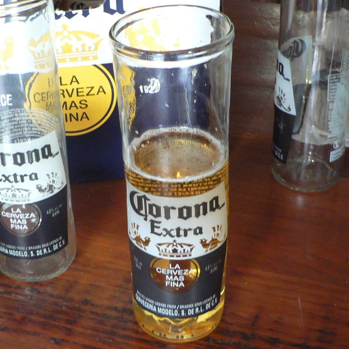 glass half full sitting on a brown table with bottles beside it