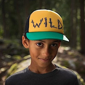 child wearing a yellow front panel green brim hat with wild written in stick like figures