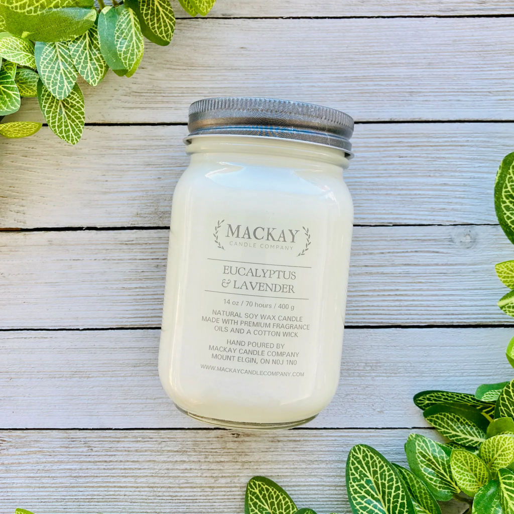 Mason jar filled with white candle, pewter lid and clear label with MacKay and other info