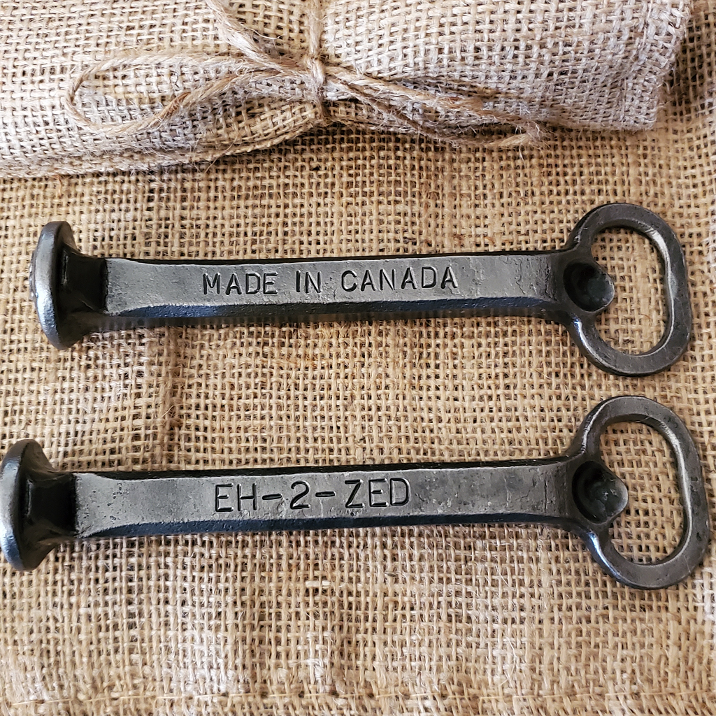 Two railway spikes turned into bottle openers. One says Made in Canada and the other says Eh-2-Zed