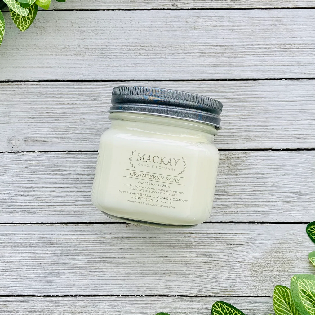 Mason jar filled with white candle, pewter lid and clear label with MacKay and other info