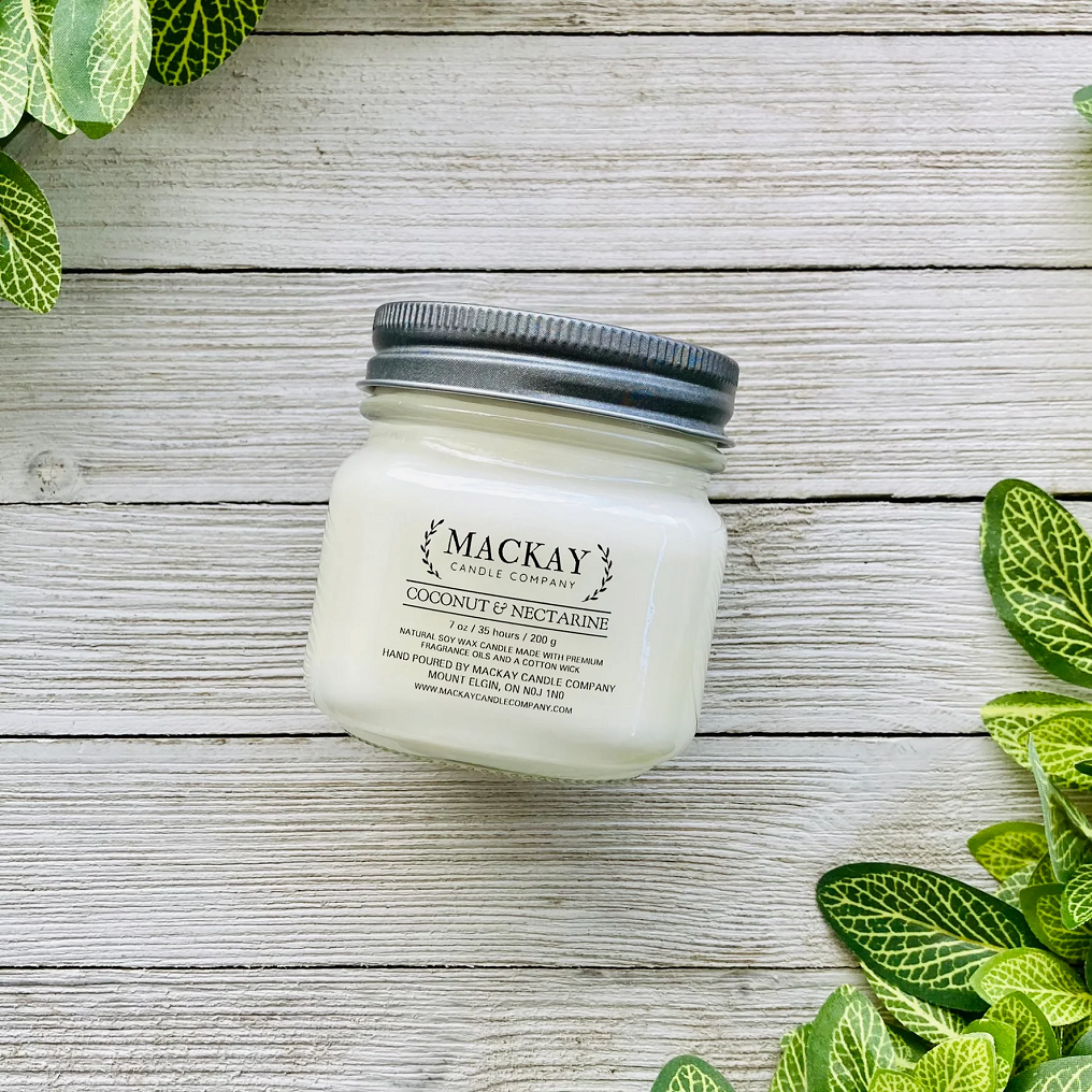 Mason jar filled with white candle, pewter lid and clear label with MacKay and other info