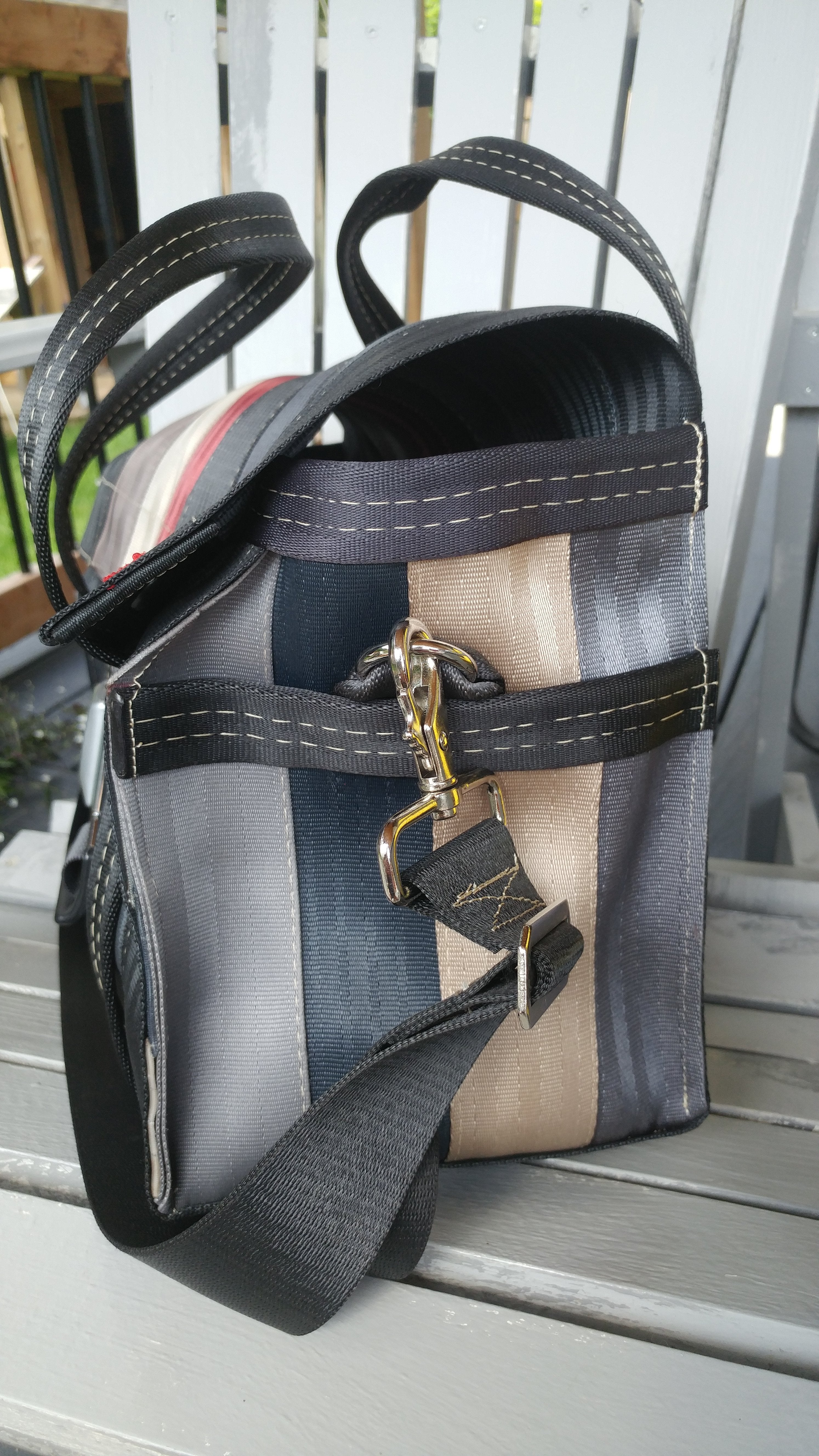 side view of bag sitting on a chair looking at the metal hook closure for the long strap