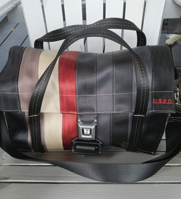 bag siting on a chair buckled up small handles up and strap down